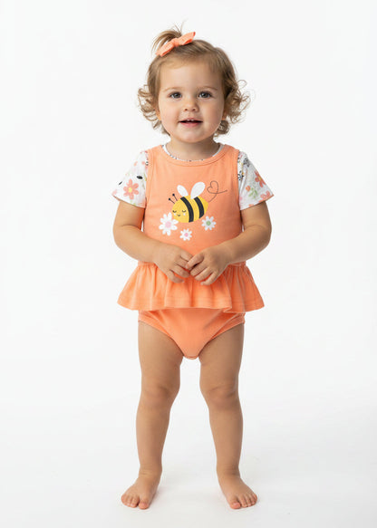 Baby outfit with orange top and bloomers featuring a bee design, hanging against a red background.